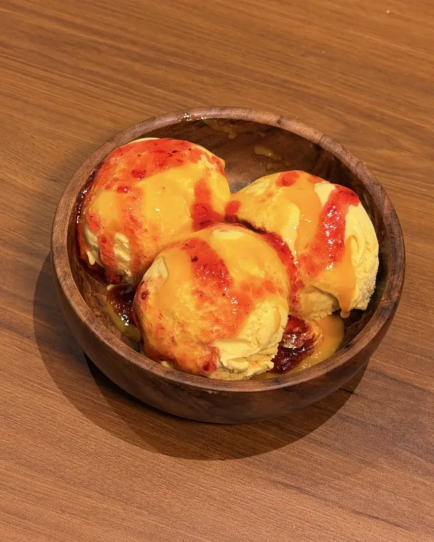 Mango Raspberry sundae: three scoops of mango ice cream with raspberry sauce in a wooden bowl